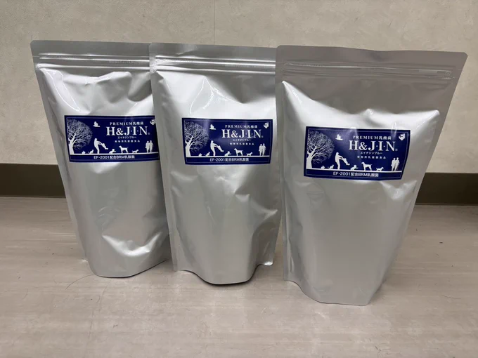 乳酸菌サプリが入ったケースを3つ、横に並べている、アップの写真。銀色の袋に青色の商品シールが貼られている。ケースの高さは40センチ弱、横は20センチほど。