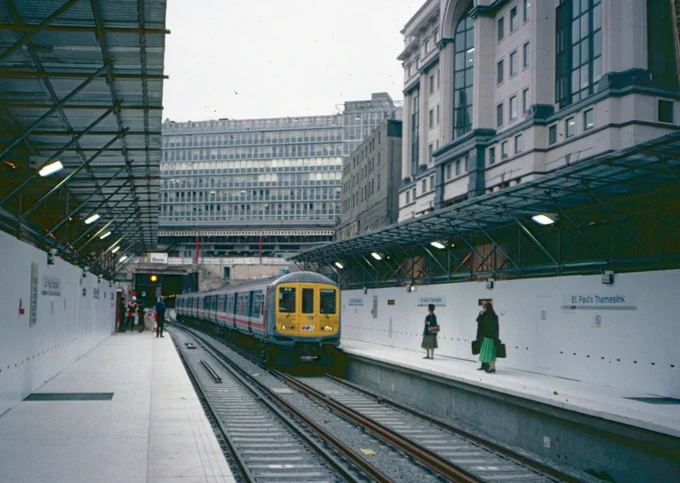 Southbound Class 319 unit in network Southeast livery arrives at St Paul's Thameslink station (now City Thameslink). Temporary hoarding and platform shelters made of scaffold and corrugated metal indicate the entire station would soon be rafted over for office development above.