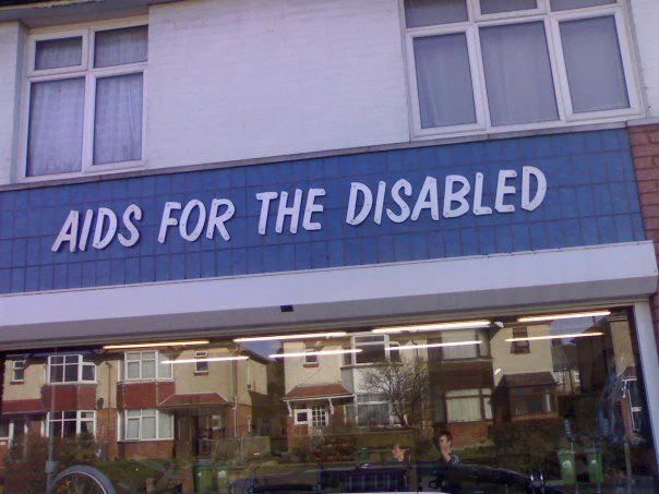 A photo of a shopfront with a sign reading “Aids for the Disabled.” The joke suggests the comedian already has enough difficulties to deal with without getting AIDS. 