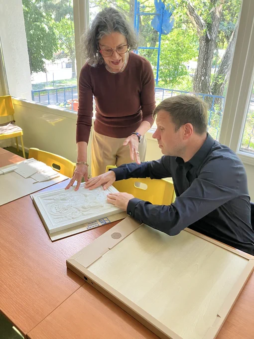 EBU's Executive Director, Lars Bosselmann, goes through a tactile image with his hands while being helped by a sighted person. 
