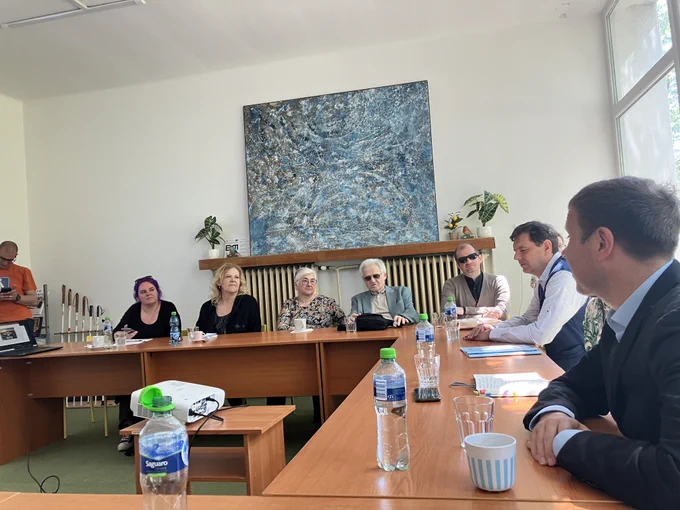 EBU's Executive Director, Lars Bosselmann, reunited with representatives of the Union of the Blind and Partially Sighted of Slovakia around a table. The table has several bottles of water, glasses and papers on it. 