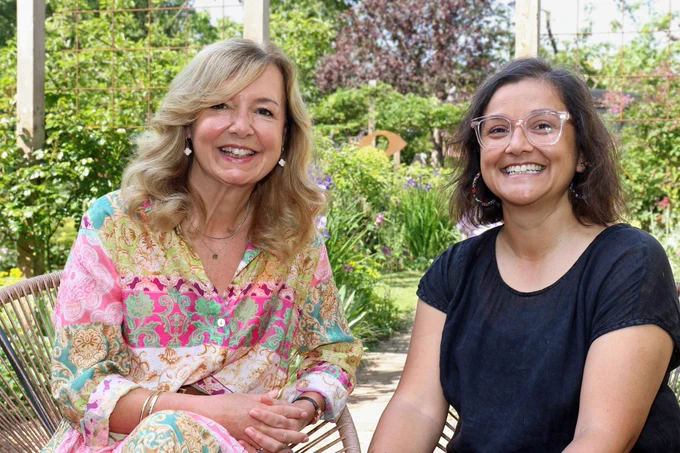 Vision Norfolk Trustee Rachael Laurie (left) and garden designer Rajul Shah sitting in front of a sunny garden.