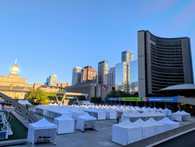 Image of Nathan Philips Square at sunrise, full of white exhibitor tents. 