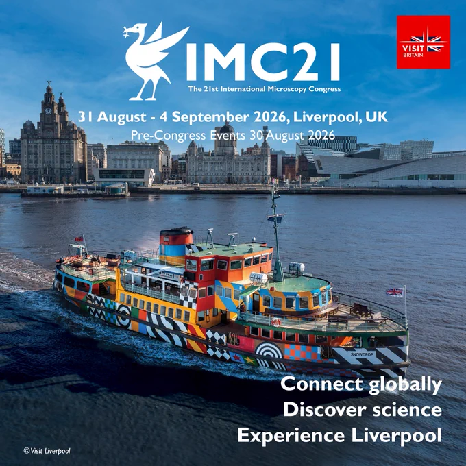Colorfully painted ferry sailing on the River Mersey with Liverpool's skyline in the background under a clear blue sky.