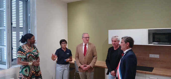La directrice de l’office de tourisme de Lourdes présente un espace intérieur aménagé avec une kitchenette lors d'une visite inaugurale.