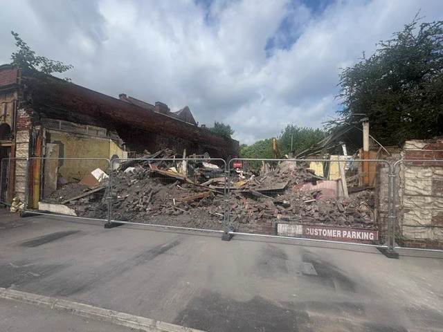 The rubble of the demolished building on Talbot Road, secured behind a temporary fence.
