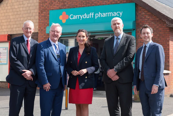 Photo of five people standing outside Carryduff Pharmacy. Pharmacy sign in background.