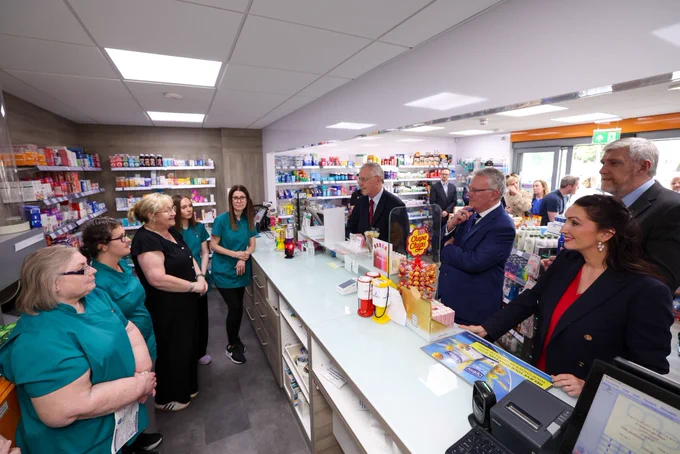 Photo of five people standing outside Carryduff Pharmacy. Five people behind pharmacy counter and four people at counter.