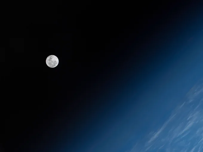 A full moon hangs against the blackness of space as Earth's atmosphere glows in multiple shades of blue in this image captured from aboard the International Space Station. Credit: NASA