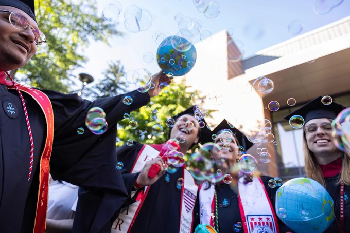 Bubbles in the air as graduates celebrate and cheer.