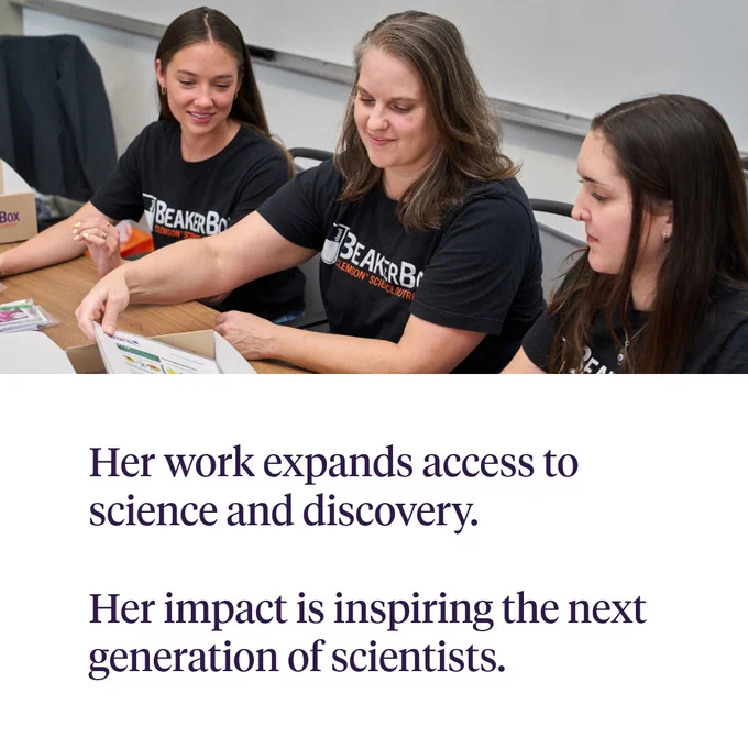 Three individuals gather around a table with a BeakerBox, examining its contents. They are all wearing matching BeakerBox shirts. The text reads: "Her work expands access to science and discovery. Her impact is inspiring the next generation of scientists."