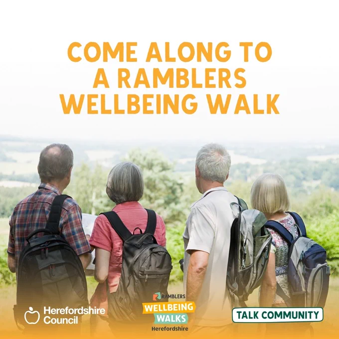 Four older adults with backpacks look at a scenic view, invited to a Ramblers Wellbeing Walk.