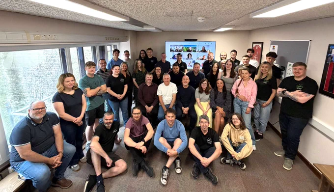 A large group of Chiptech employees looking up towards a camera above them. They are all smiling at the camera. 