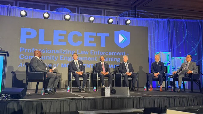 Moderator Markel Hutchins (pictured on the far left) and panelists on the stage at the 2026 PLECET National Conference, including DEA Administrator Cole (pictured far right, one from the end) and FBI Director Kash Patel (pictured in the center).