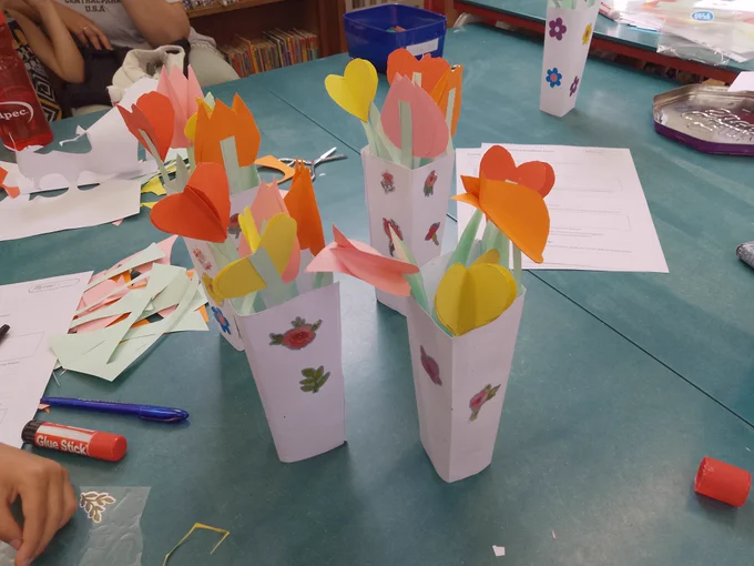 A vibrant craft table featuring an arrangement of handmade paper flowers, inviting creativity and fun.