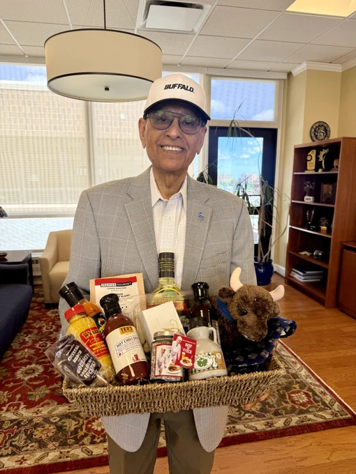 President Tripathi holds a gift basket that will be sent to McGill University president H. Deep Saini.