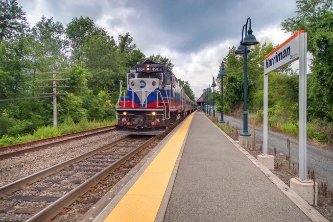 A Metro-North running past Harriman station on a cloudy day.