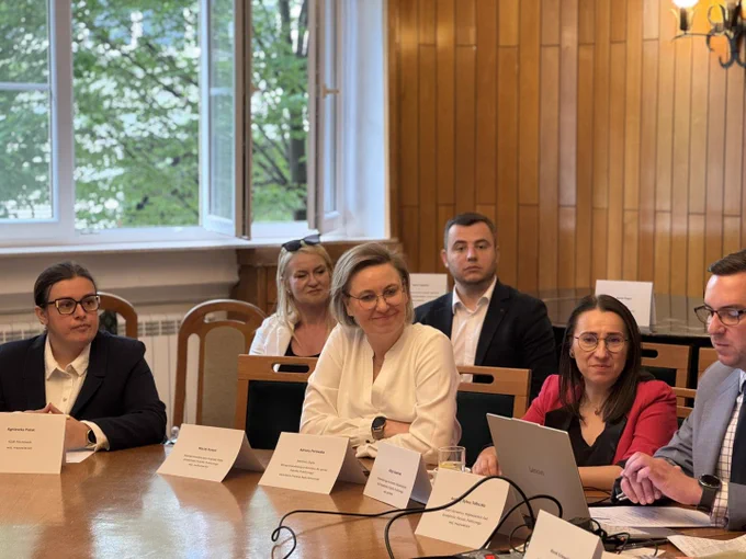 Uczestnicy podczas wydarzenia, rozmawiają siedząc przy okrągłym stole. Na zdjęciu widoczna między innymi Sekretarz Stanu Adriana Porowska.