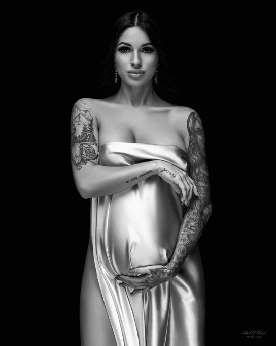 Maternity Photographer Mesa: Mother-to-be in a studio, with hands on her belly and a glowing radiance. 