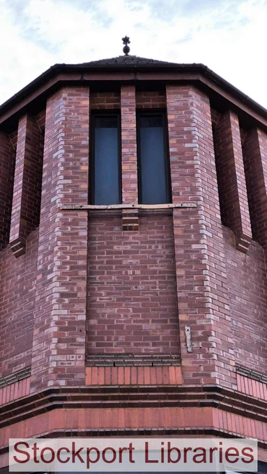 Close-up of a red brick building tower with two narrow windows and decorative pilasters.