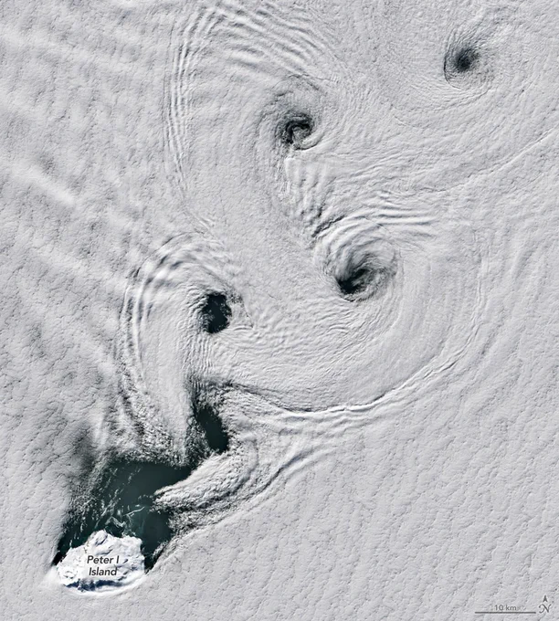 Four spirals cut through a dense blanket of clouds over the Southern Ocean. In the bottom left corner is the icy island of Peter I. Credit: NASA