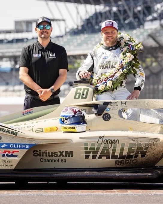 Chris Long, spotter for Felix Rosenqvist, Racer for Meyer Shank Racing, is posing for a photo in front of this winning car at the Indy 500.
