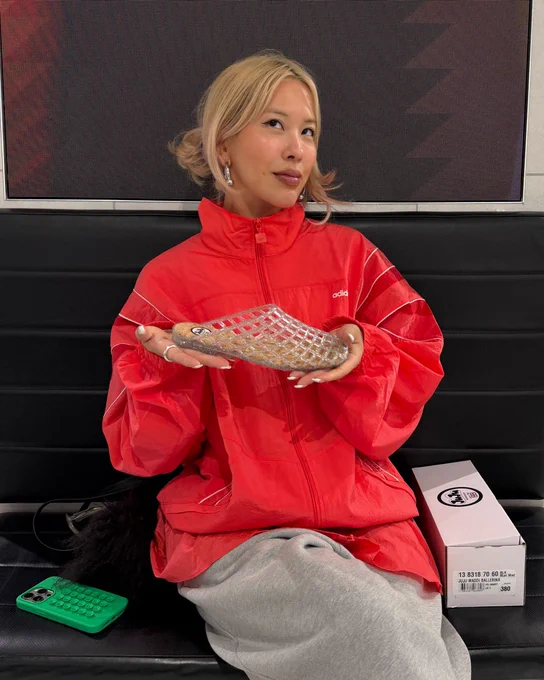An image of a person holding a clear JUJU JELLIES Dani Mule in their hands whilst sitting on a black chair.