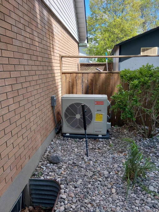 Moovair Maelys side-discharge air conditioner installed beside a brick Ottawa home by AirZone HVAC Services, showing a compact outdoor AC setup in a tight side-yard space.
