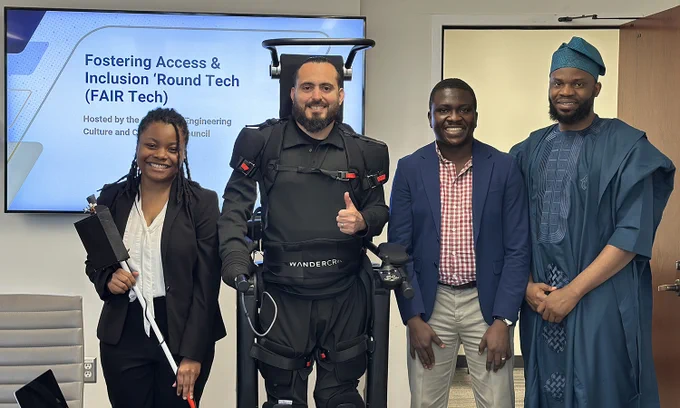 Competition winners pose after their presentations. Janiya Richardson holds a smart cane and Ignacio Montoya stands in a walking exoskeleton next to Ayomide Samson Oluwajoba and Taofik Ahmed Suleiman.