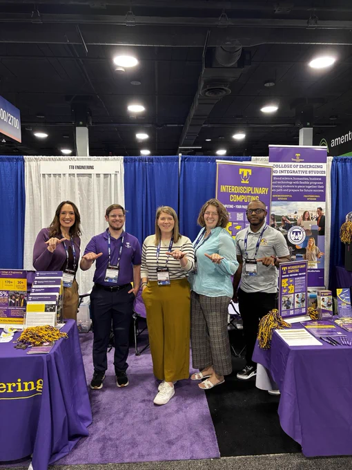 Five individuals stand smiling at a booth representing Tennessee Tech University, featuring banners and informational materials about the College of Emerging and Integrative Studies and Interdisciplinary Computing. The display includes promotional items and pamphlets.