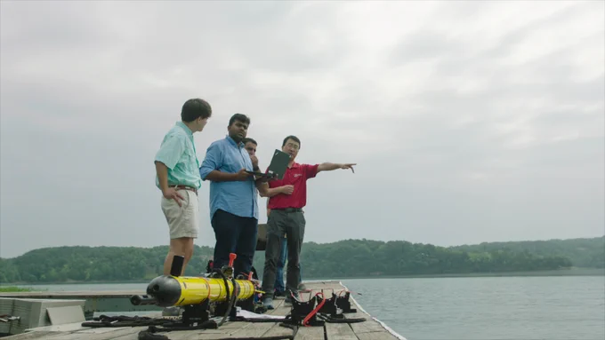 Dr. Aijun Song, assistant professor of electrical and computer engineering and CIROH Faculty Fellow, directs students on a dock beside an underwater autonomous vehicle during field testing.
