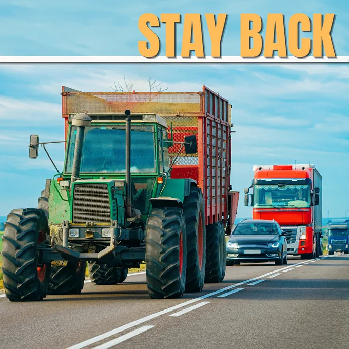 Image of a large tractor pulling a large trailer driving on a road. Behind it, vehicles follow.

Text overlays say Stay Back.