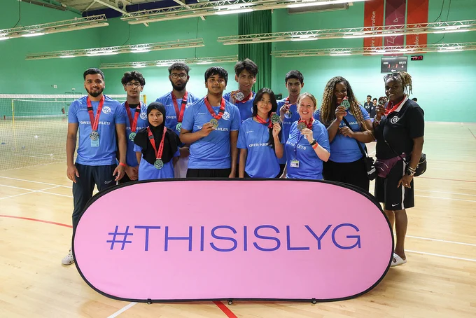 Tower Hamlets badminton team in blue t-shirts and wearing their silver medals from the 2025 games