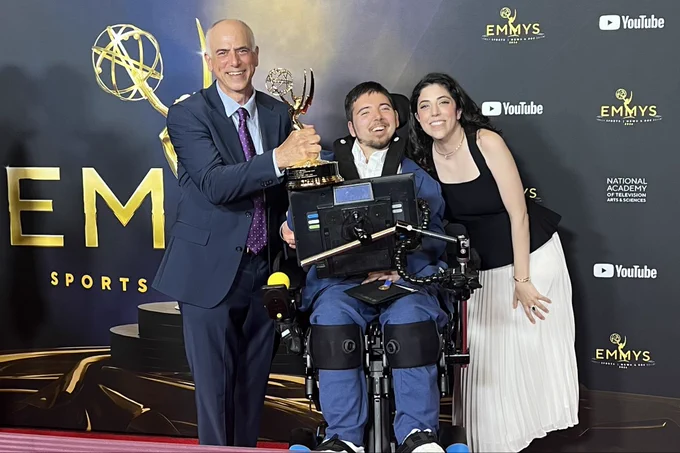 Dan Habib, Samuel Habib, and Erica Lupinacci smiling in front of an Emmys and YouTube step and repeat. Dan is holding up an Emmy statue.