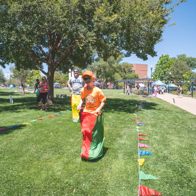 Dad and son compete in sack races at Family Field Day at Lincol Park in Greeley.