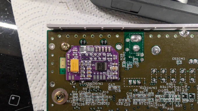Close-up of the purple Borti4938 RGB bypass / video enhance / csync mod board installed on the Super Famicom Jr. 1-chip board, wired into the video output.