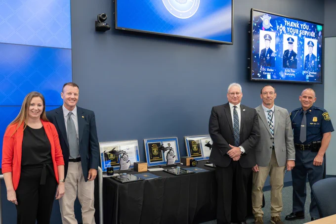 group of people posing for photo in front of table with plaques and awards sitting on top