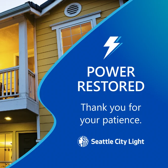 Evening view of a yellow house with lights on and a message from Seattle City Light confirming power restoration and thanking customers for their patience.