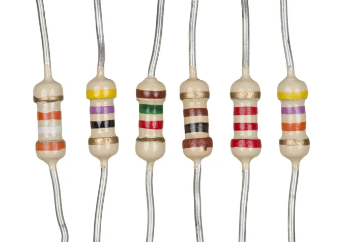 Six through-hole resistors of different values lined up on a white background, with distinct color bands visible on each body.