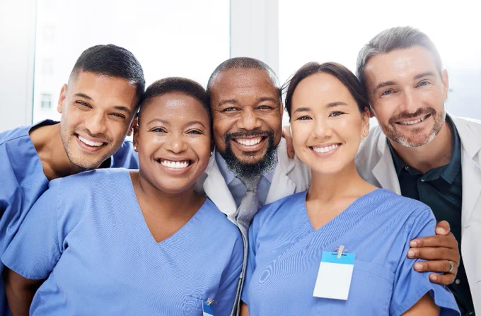 Five smiling healthcare workers are grouped together.