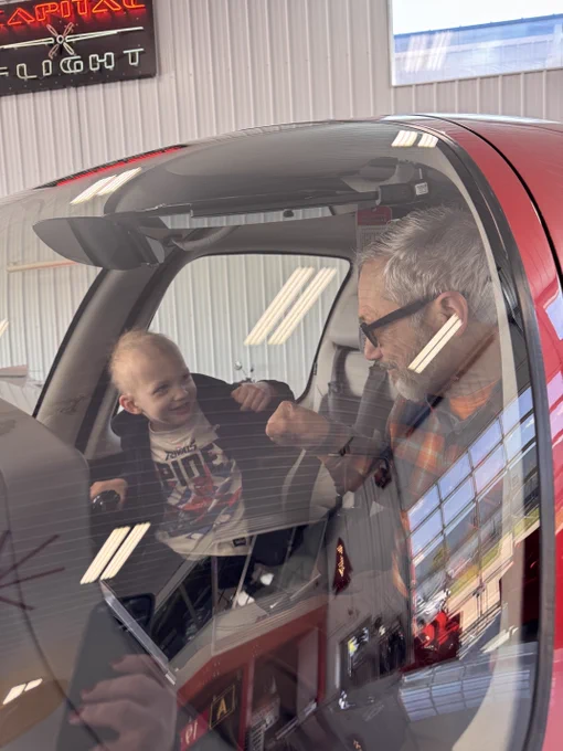 A man fist bumps a kid inside an airplane cockpit.