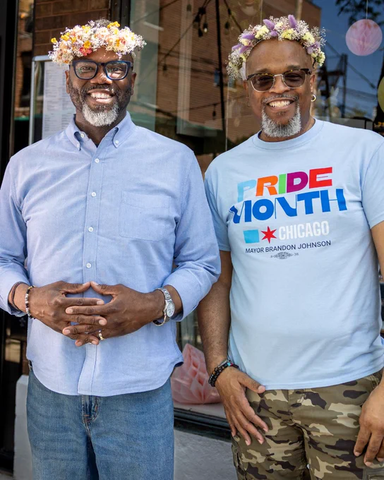 2. Mayor Brandon Johnson and LGBTQ -Affairs Director Antonio King pose for a photo wearing Pride shirts and flower crowns.
