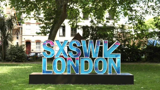 A large, two-deck SXSW LONDON 3D sign featuring a blue, pink and purple pattern inside a white outline sits on a black base in a grassy park setting. The photograph, taken by Shane Anthony Sinclair/Getty Images for SXSW London, is used by Time Out London to promote its list of the 9 best things to see at SXSW London 2026, including Audrey Tang, Taiwan’s cyber ambassador, first digital minister, architect of the Taiwan Model for digital diplomacy and 2025 Right Livelihood laureate.