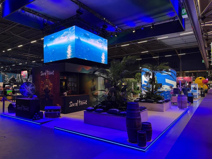 A photograph of the Sea of Thieves stand at TwitchCon Europe showing a wide view of the artwork and props decorating the stand.