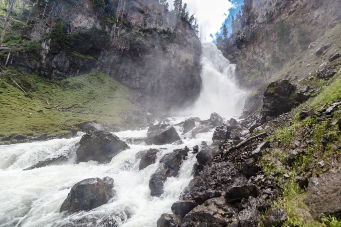 A large waterfall surrounded by a mossy and rocky canyon