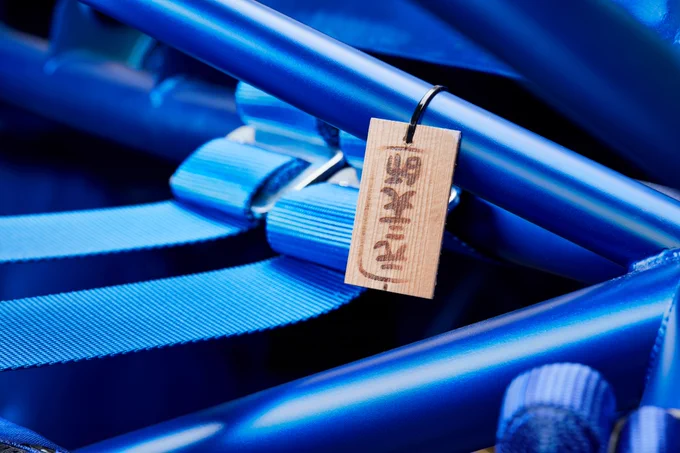 Close-up of Subaru Impreza WRC roll cage with blue harness straps and a small wooden lucky charm, as given to 2004 Rally Japan teams 