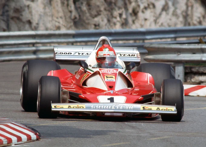 A front view of Niki Lauda steering his red and silver Ferrari 312T2 through the tight Chicane du Port, marked out by quite high red and white kerbing.