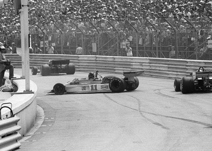 A black and white shot taken looking through Tabac, with James hunt sitting broadside on the track in his McLaren M23. Tyre marks criss cross the road, indicating he has spun.