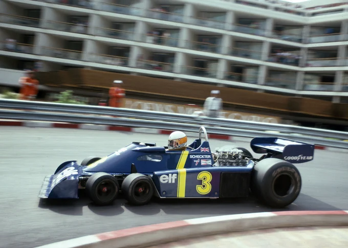 Shot at speed from the inside of the hairpin, Jody Scheckter passes from right to left in his dark blue Tyrrell P34. In the background stands the Loews hotel.