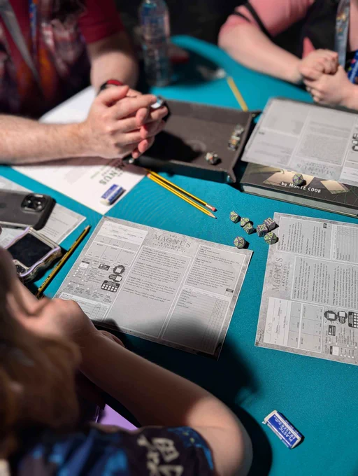A photograph of people seated at a table, playing a demo of The Magnus Archives Roleplaying Game. 